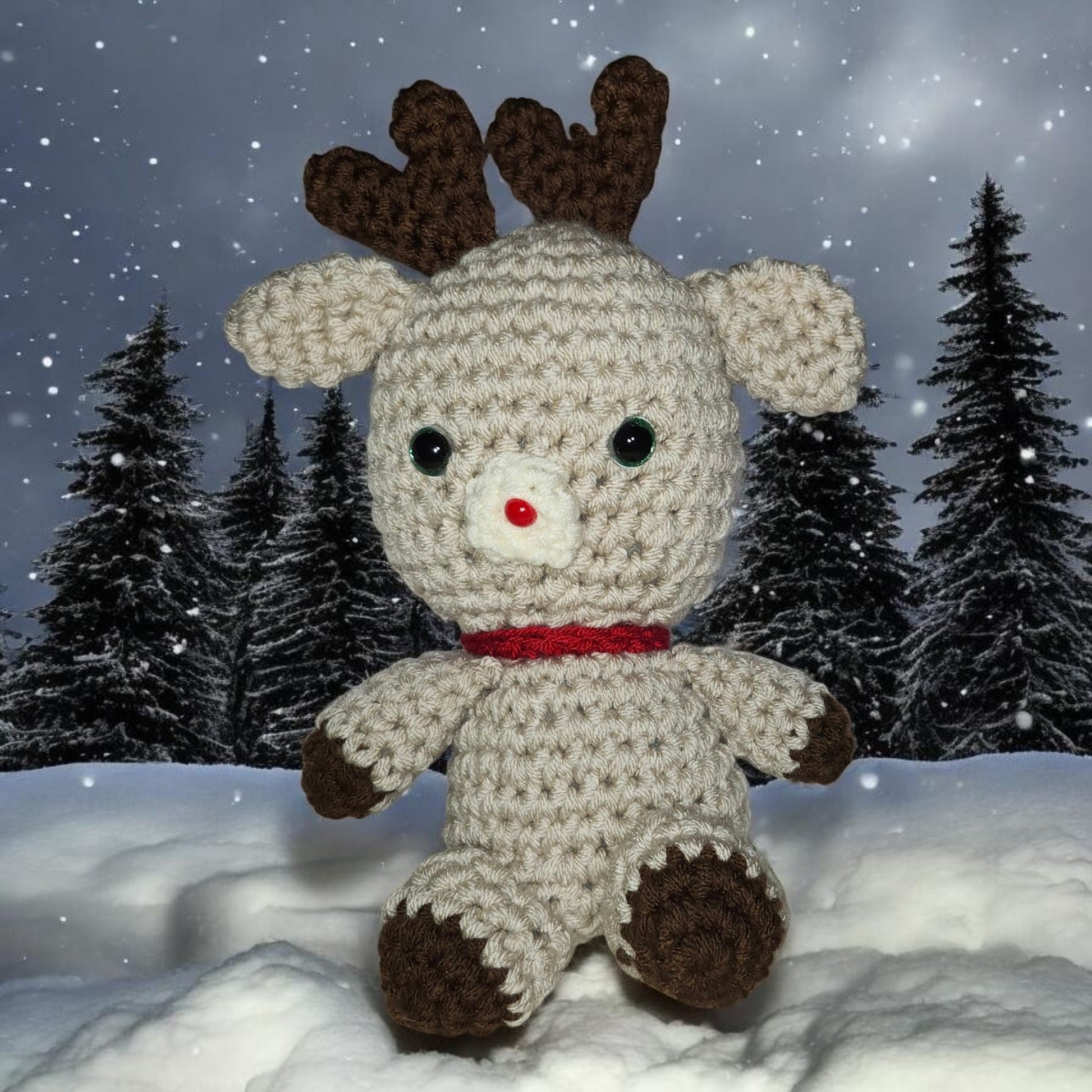 Handmade crochet sitting reindeer wearing a scarf and displayed against a neutral background.