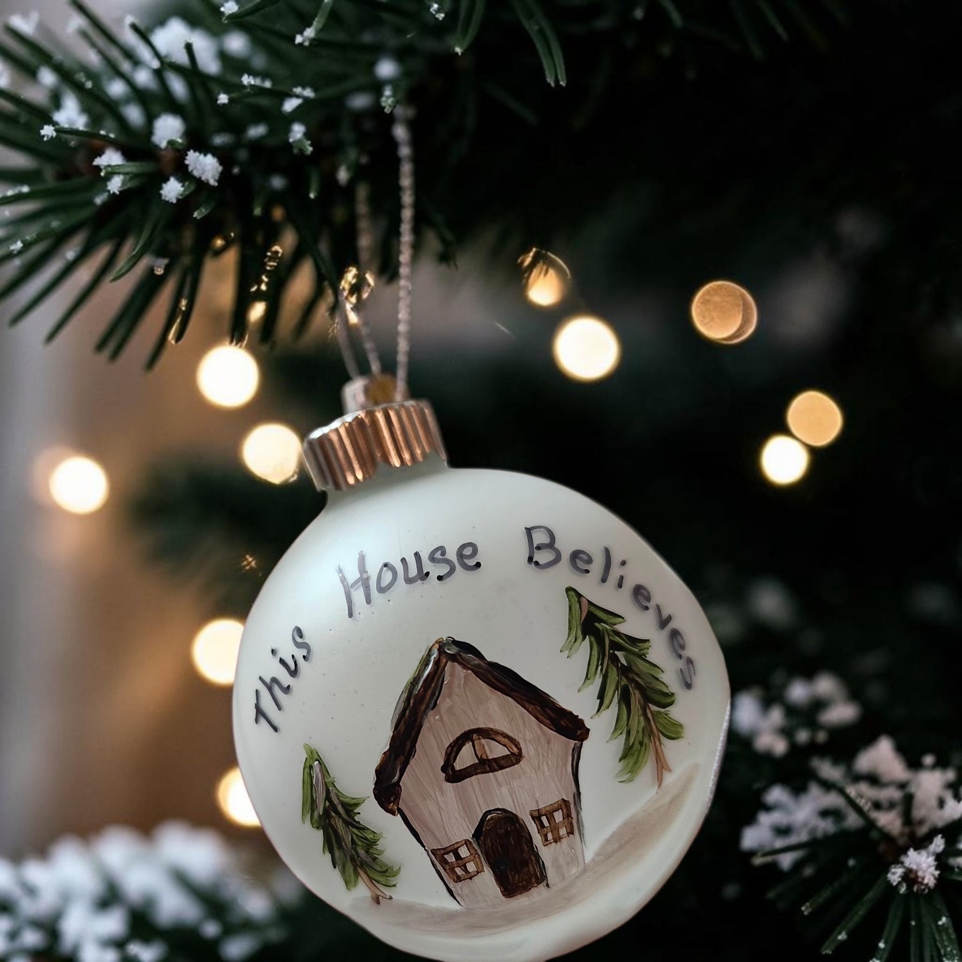 Hand-painted This House Believes glass Christmas ornament with house and evergreen trees
